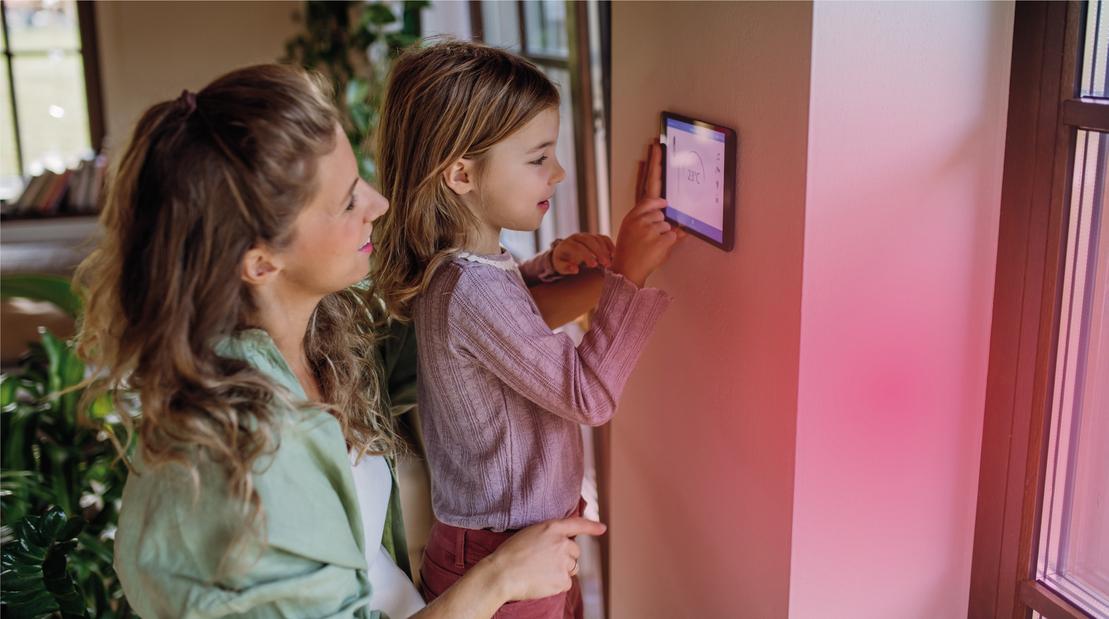 Gas Stadtwerke Ostmünsterland - Eine Frau und ein Mädchen stellen die Heizung über ein Panel ein. Gas Stadtwerke Ostmünsterland - Eine Frau und ein Mädchen stellen die Heizung über ein Panel ein.