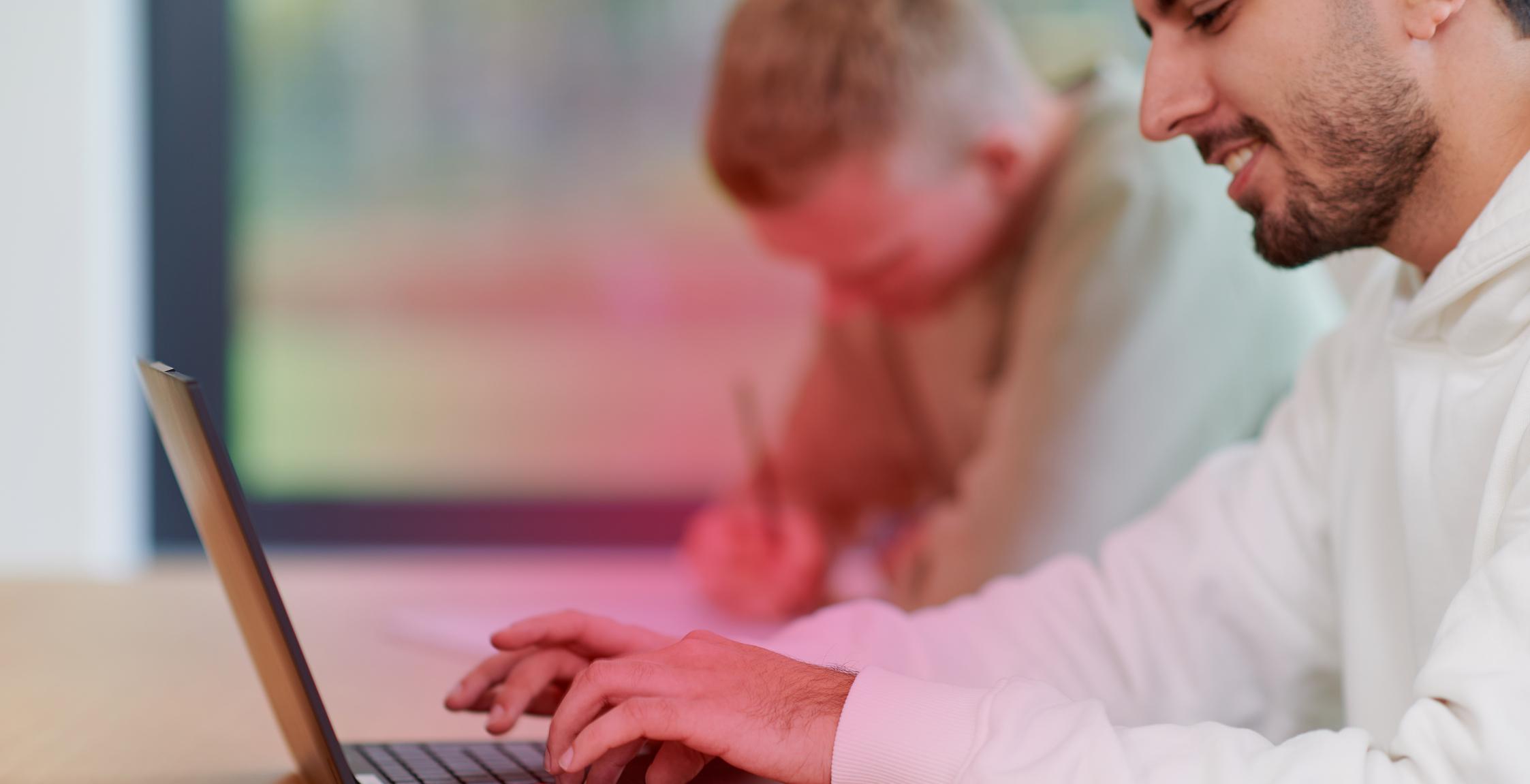 Zwei junge M&auml;nner sitzen an einem Schreibtisch und haben einen Laptop vor sich