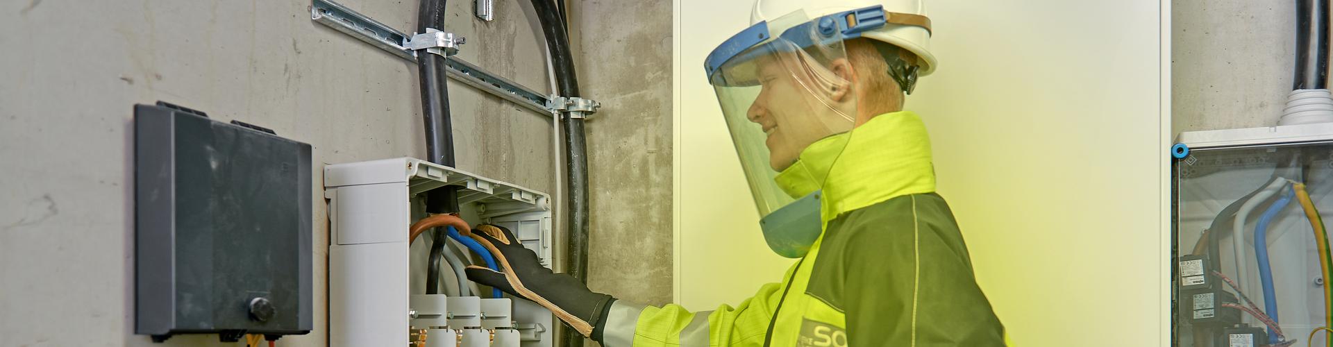 Ein Elektriker arbeitet in Schutzkleidung am Hausanschluss