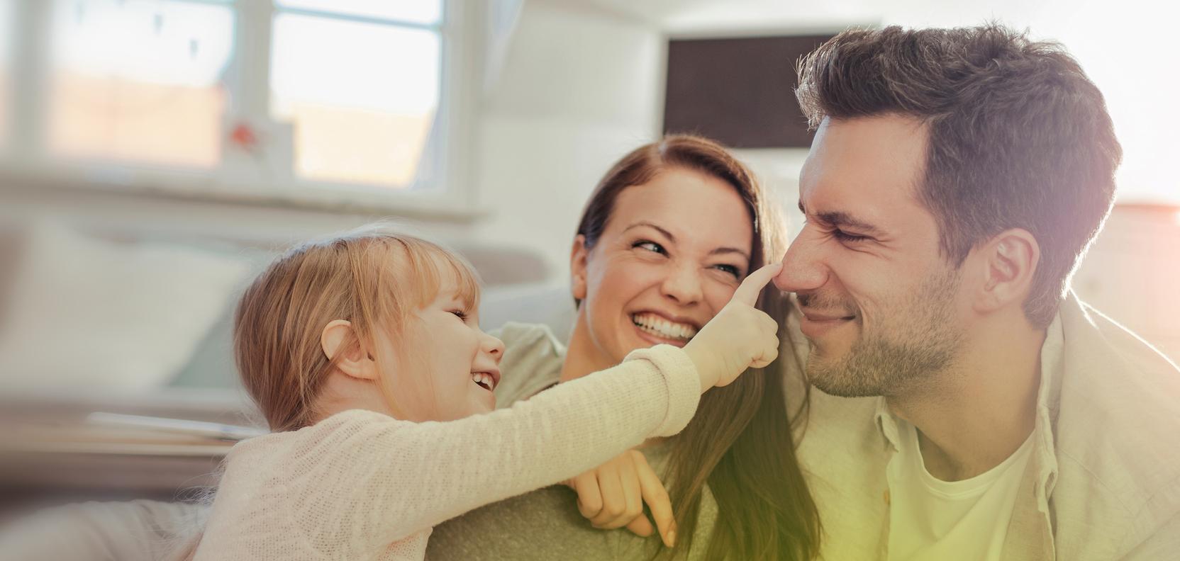 Eine Frau und ein Mann kuscheln zu Hause mit einem kleinen Mädchen. Eine Frau und ein Mann kuscheln zu Hause mit einem kleinen Mädchen.