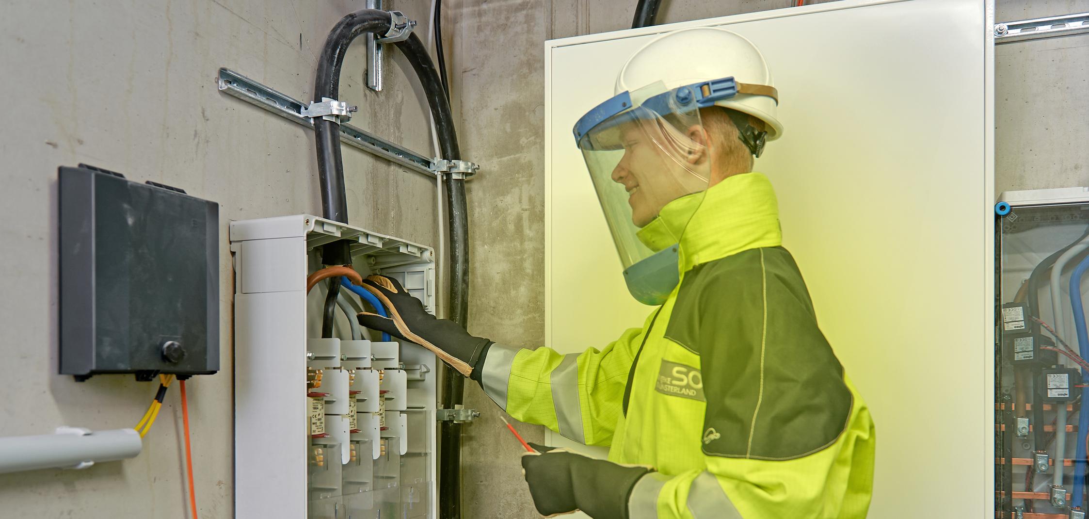 Ein Elektriker arbeitet in Schutzkleidung am Hausanschluss Ein Elektriker arbeitet in Schutzkleidung am Hausanschluss