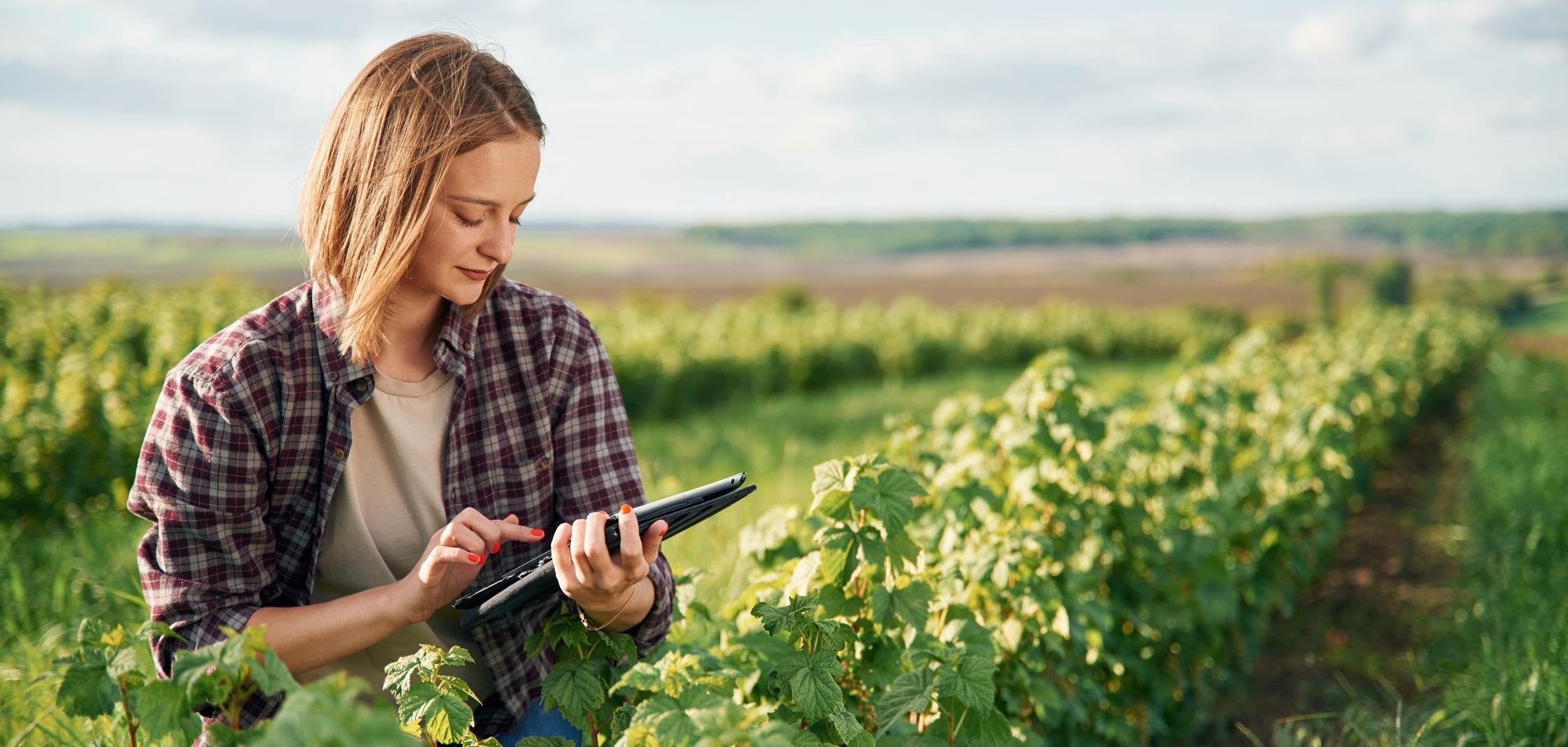 Eine Landwirtin vor einem Feld mit einem Tablet in der Hand Eine Landwirtin vor einem Feld mit einem Tablet in der Hand