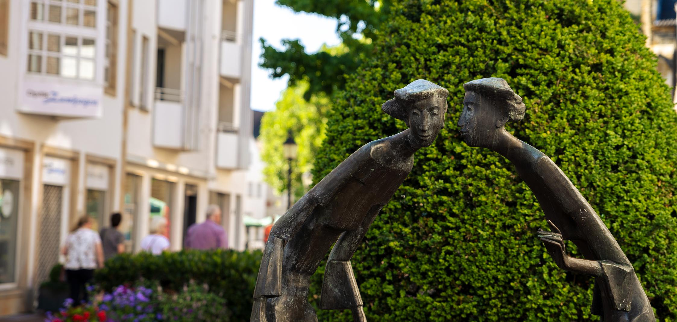 Eine Skulptur aus Bronze, die zwei Frauen zeigt, die sich etwas erzählen