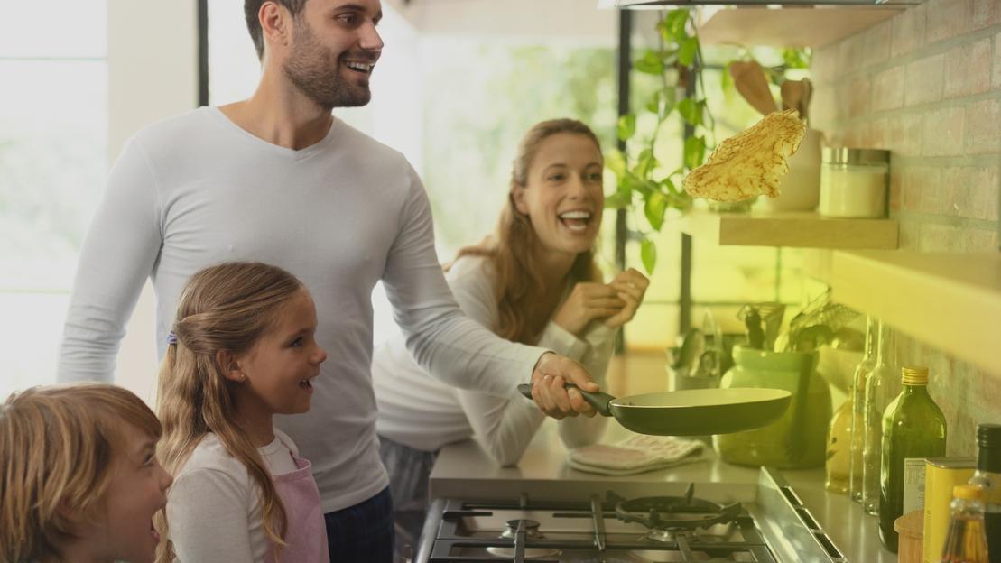 Eine Familie steht vor einem Gasherd und kocht