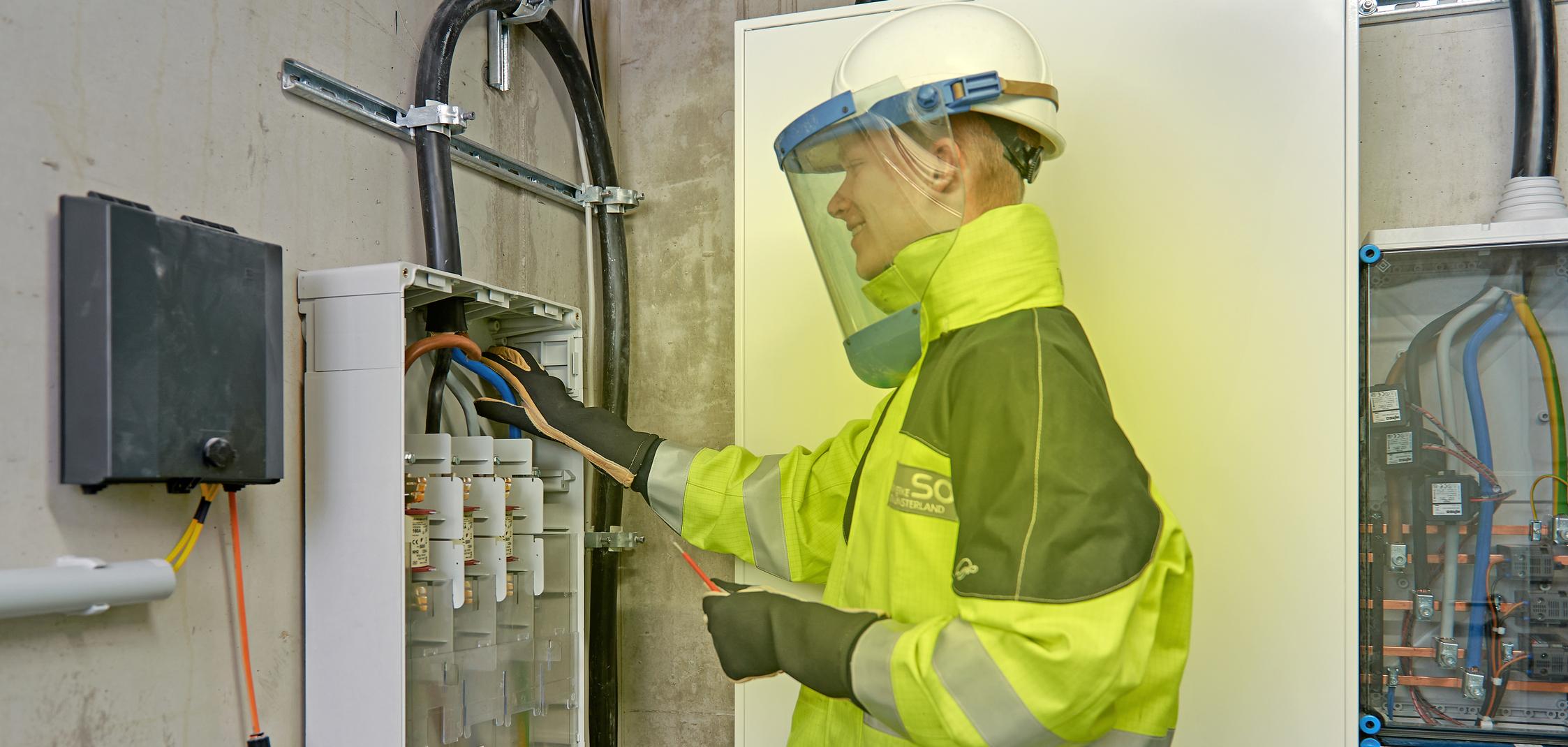 Ein Elektriker arbeitet in Schutzkleidung am Hausanschluss