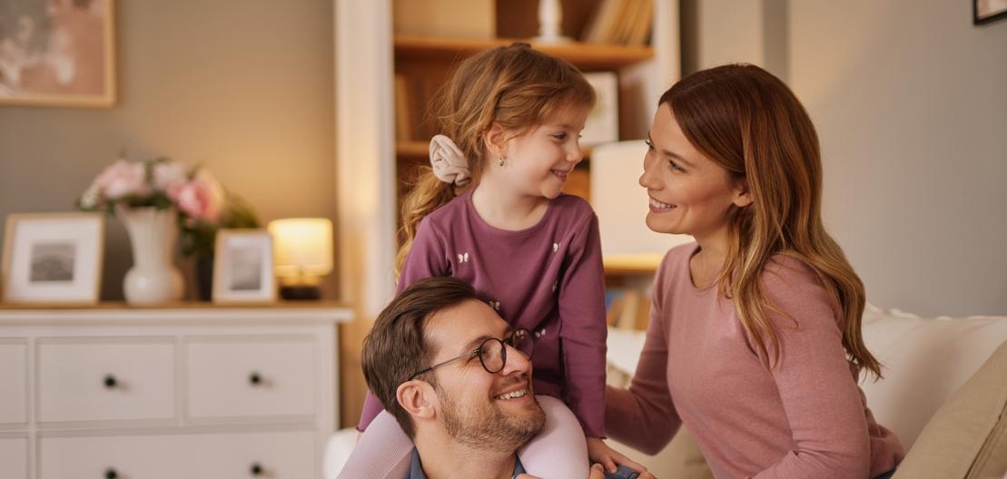 Eine Frau und ein Mann sitzen auf dem Sofa und kuscheln mit einem kleinen M&auml;dchen
