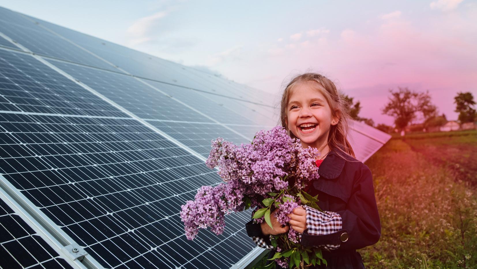Ein Mädchen steht vor einem Solarpark mit mehreren PV-Modulen Ein Mädchen steht vor einem Solarpark mit mehreren PV-Modulen