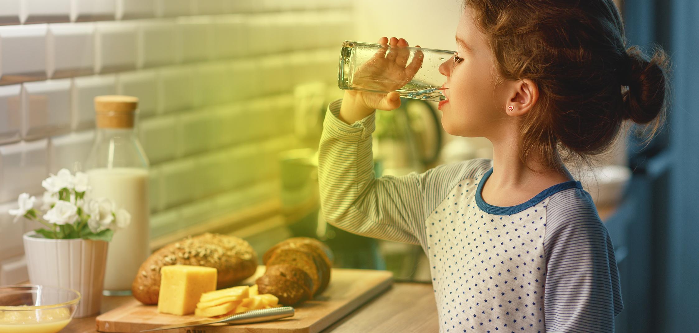 Ein Kind steht in der Küche und trinkt ein Glas Wasser Ein Kind steht in der Küche und trinkt ein Glas Wasser