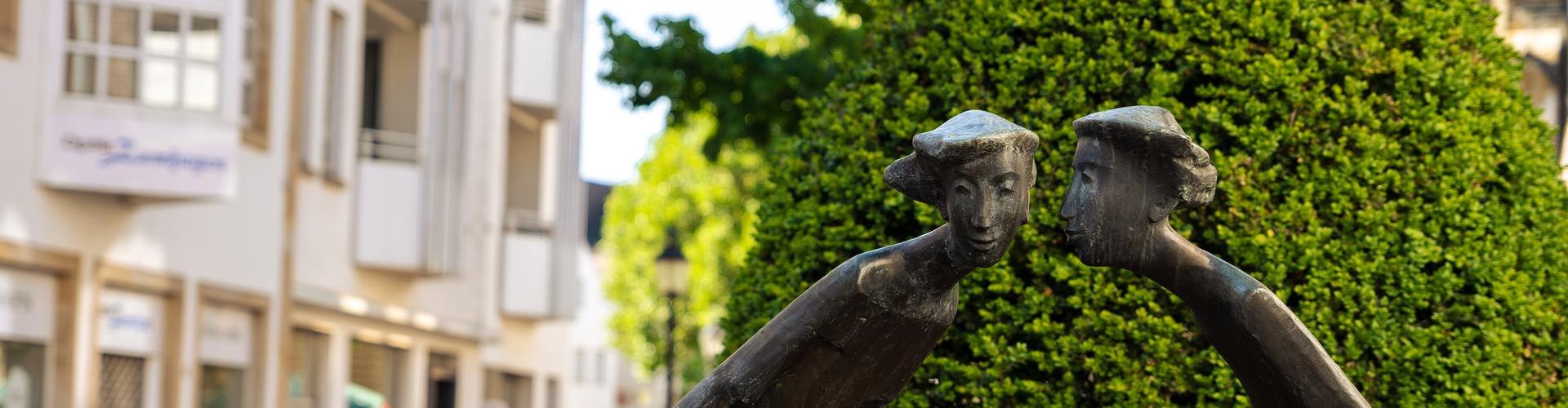 Eine Skulptur aus Bronze, die zwei Frauen zeigt, die sich etwas erzählen