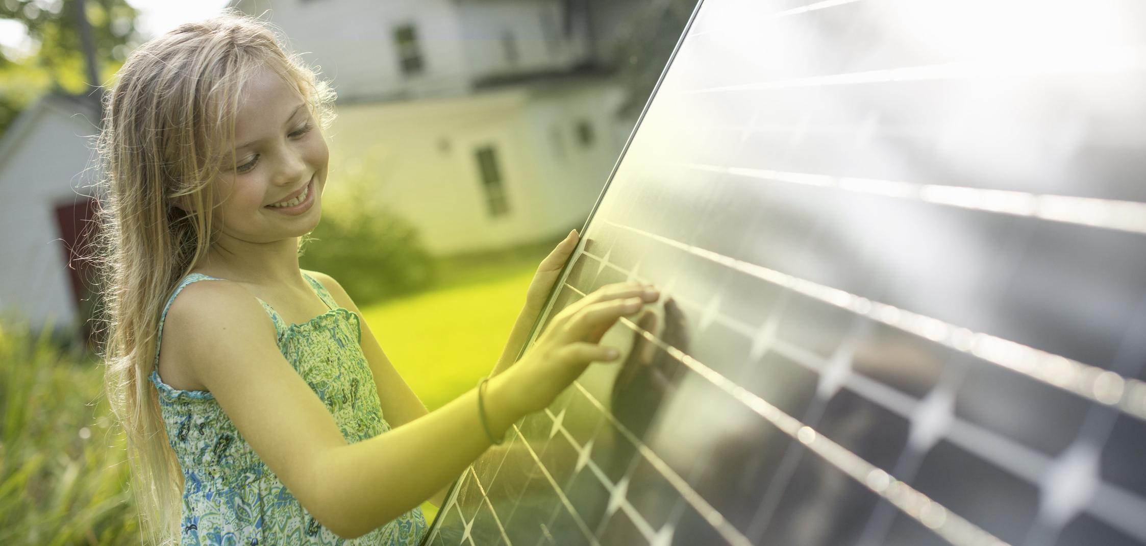 Ein Mädchen steht vor einem Photovoltaik-Modul und schaut es an