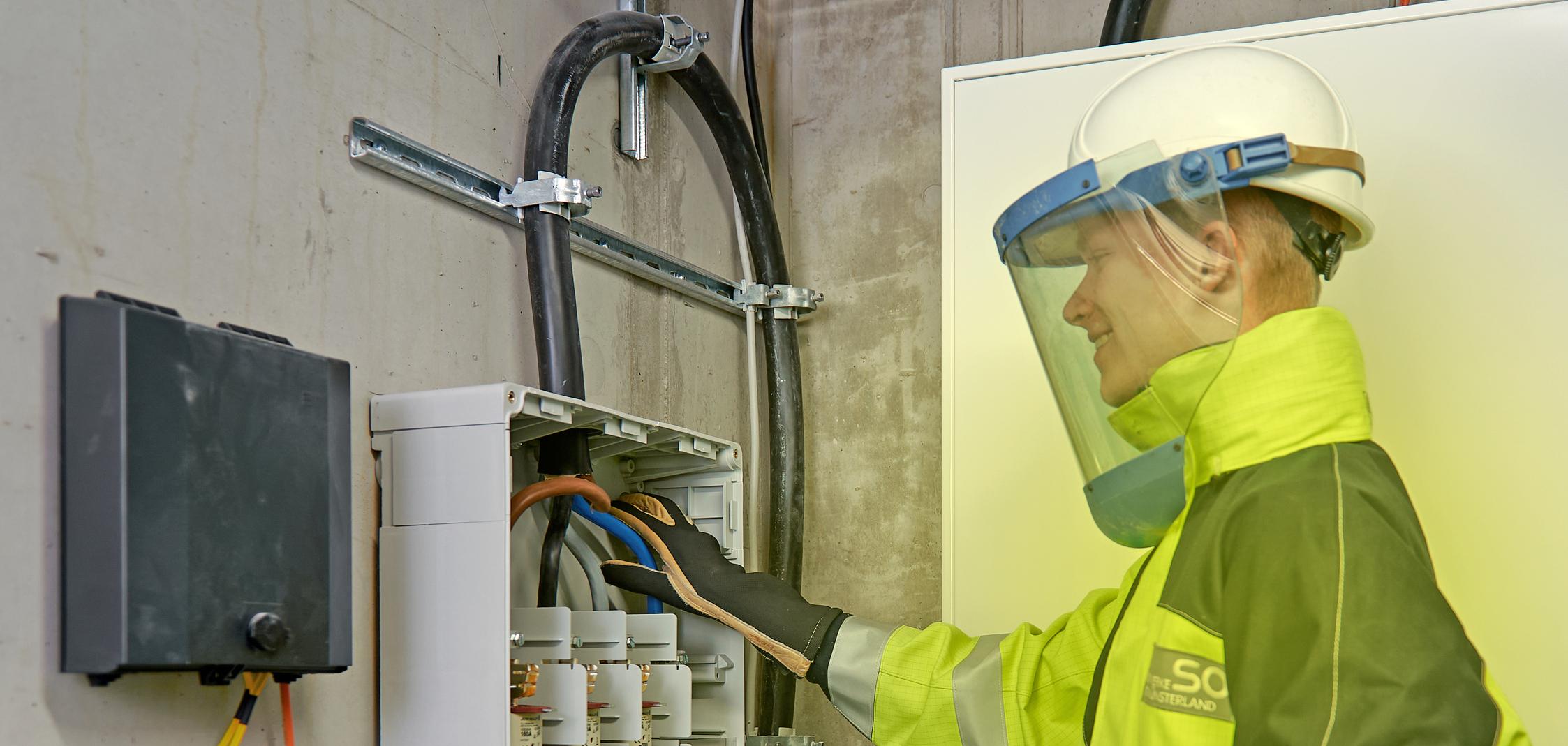 Ein Elektriker arbeitet in Schutzkleidung am Hausanschluss