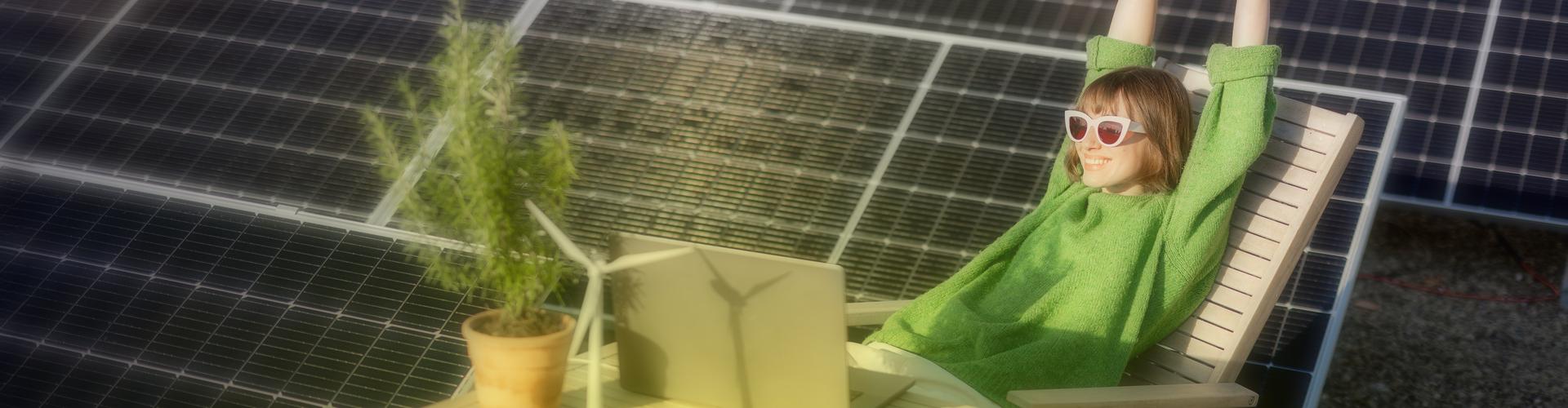 Eine Frau sitzt entspannt auf einem Liegestuhl neben PV-Modulen Eine Frau sitzt entspannt auf einem Liegestuhl neben PV-Modulen