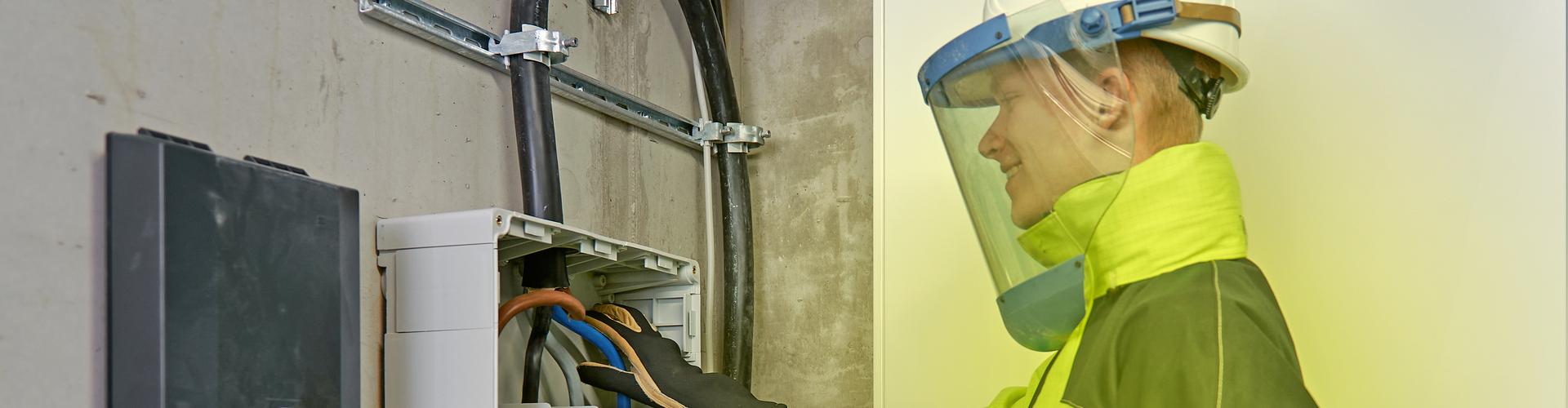 Ein Elektriker arbeitet in Schutzkleidung am Hausanschluss Ein Elektriker arbeitet in Schutzkleidung am Hausanschluss