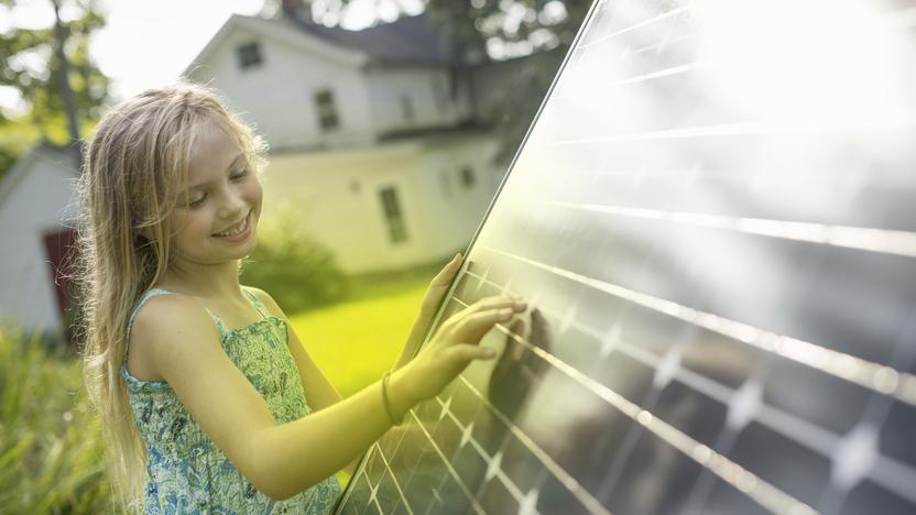 Ein Mädchen steht vor einem Photovoltaik-Modul und schaut es an