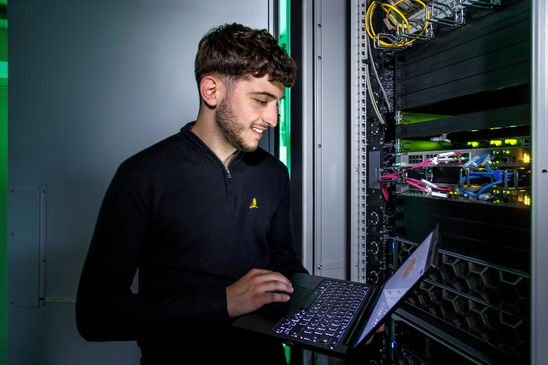 Ein IT-Mitarbeiter der Stadtwerke Ostm&uuml;nsterland &uuml;berpr&uuml;ft mit einem Laptop die Servertechnik