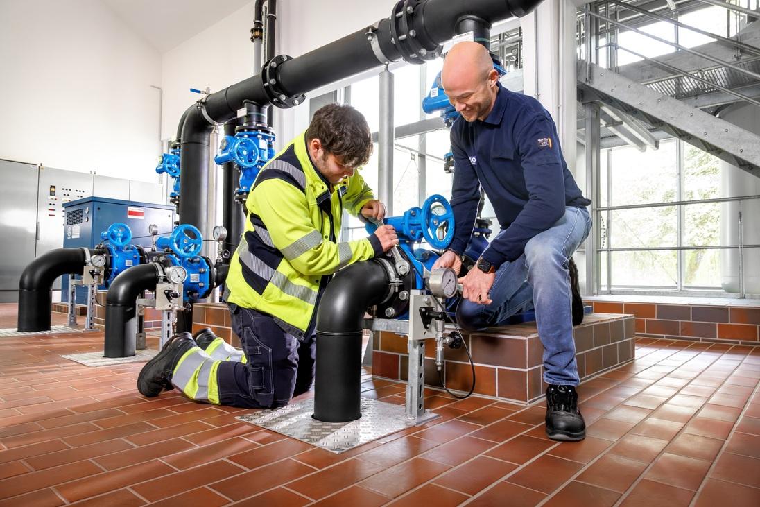 Zwei Techniker der Stadtwerke Ostmünsterland überprüfen und warten eine Wasserleitungsanlage im Technikraum, um eine zuverlässige Wasserversorgung sicherzustellen. Zwei Techniker der Stadtwerke Ostmünsterland überprüfen und warten eine Wasserleitungsanlage im Technikraum, um eine zuverlässige Wasserversorgung sicherzustellen.