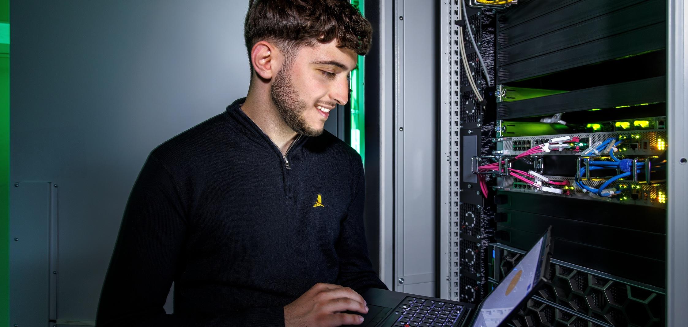 Ein IT-Mitarbeiter der Stadtwerke Ostmünsterland überprüft mit einem Laptop die Servertechnik Ein IT-Mitarbeiter der Stadtwerke Ostmünsterland überprüft mit einem Laptop die Servertechnik