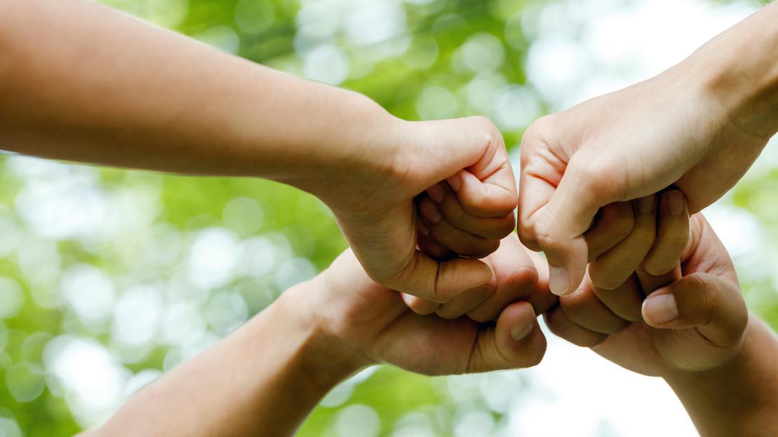Vier Menschen recken gemeinsam die Fäuste.