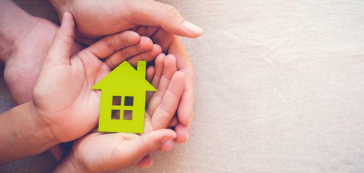 Mehrere Hände halten ein kleines Haus