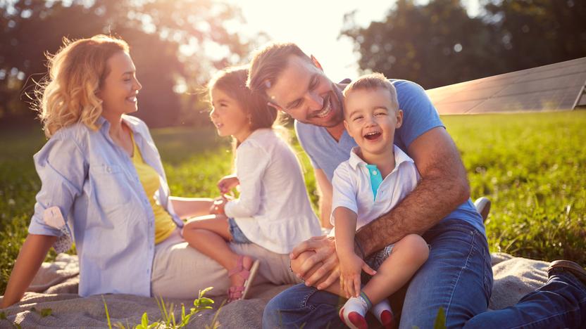Eine Familie sitzt auf einer Wiese und genießt die Sonne Eine Familie sitzt auf einer Wiese und genießt die Sonne