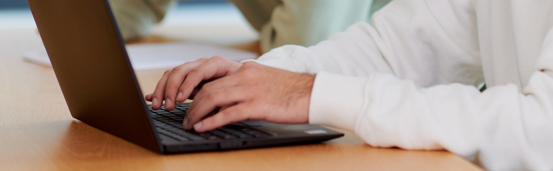 Eine Person tippt auf einem Laptop