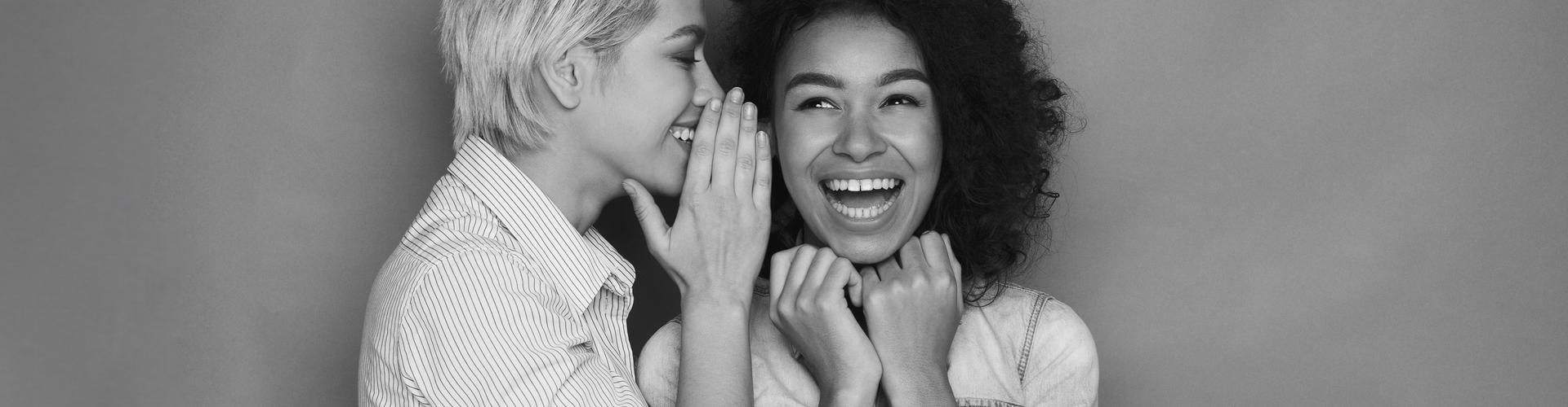 Eine Frau flüstert einer anderen Frau etwas zu